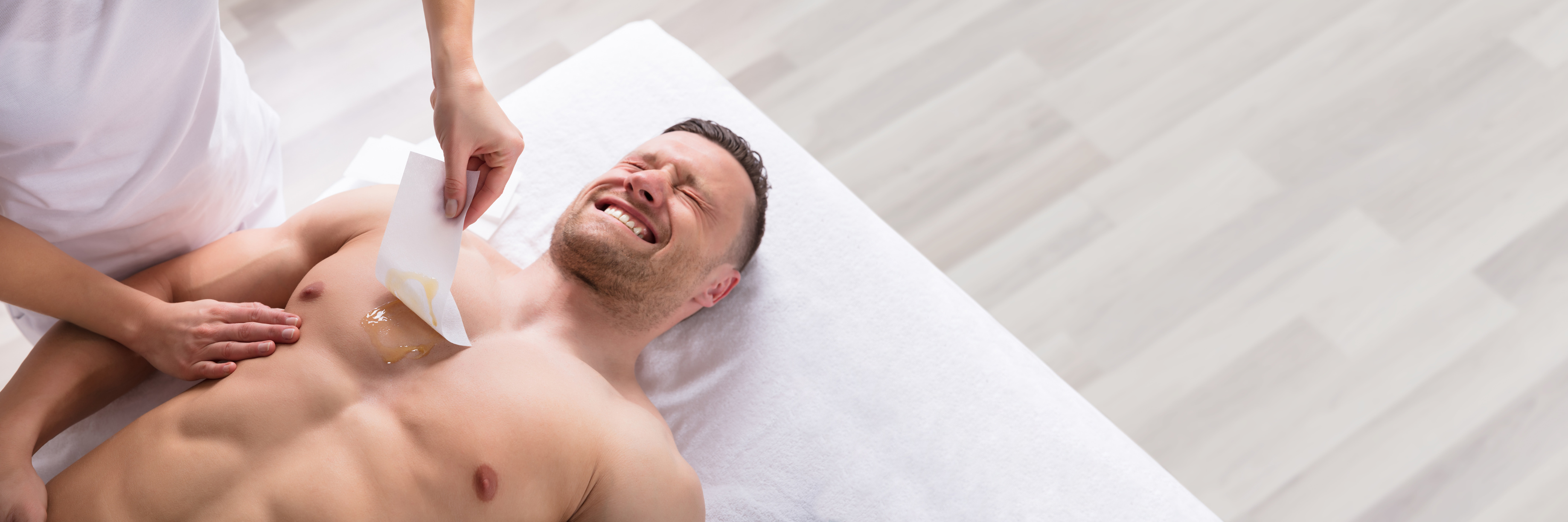 Person Waxing Man's Chest With Wax Strip